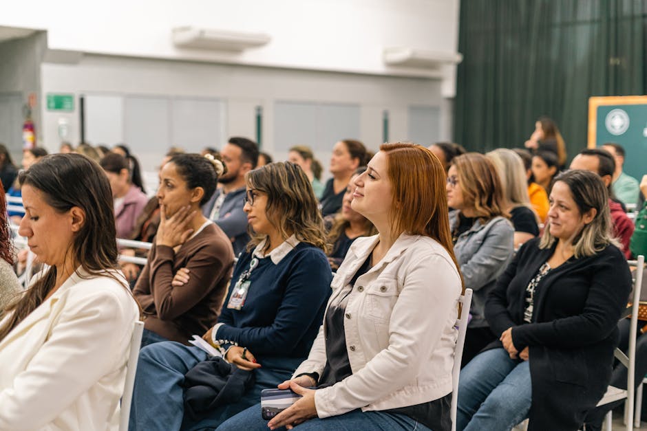 A diverse group of adults attentively listens during an indoor educational session.